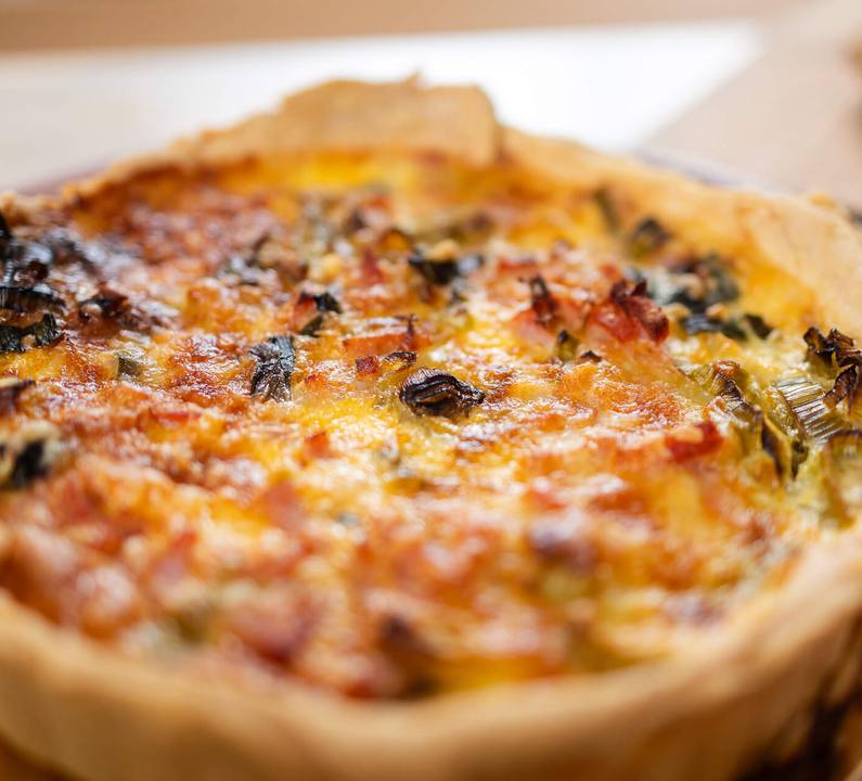 A baked quiche slice with brown bread